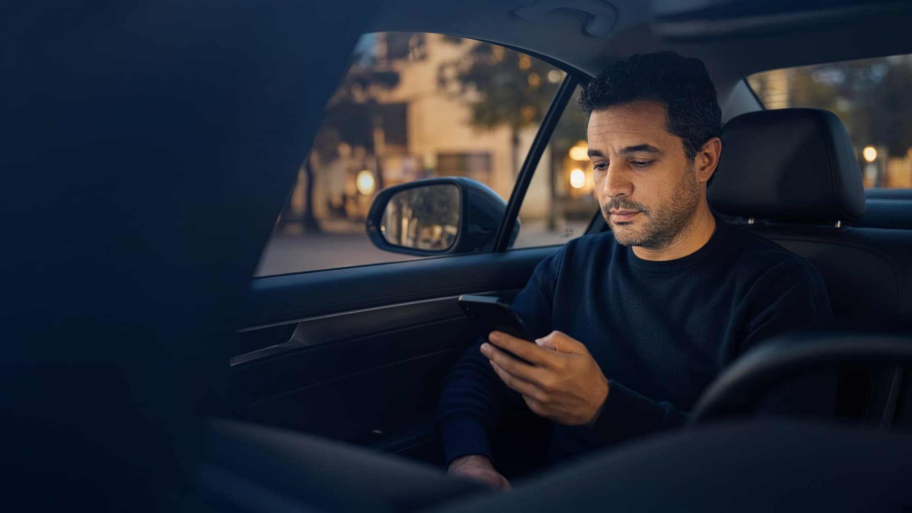 Chauffeur VTC au volant de sa berline vérifiant son contrat d'assurance sur son smartphone après la décision de l'ACPR concernant Wakam